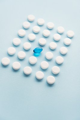 image une-capsule-liquide-bleue-dans-une-grille-de-comprimes-blancs